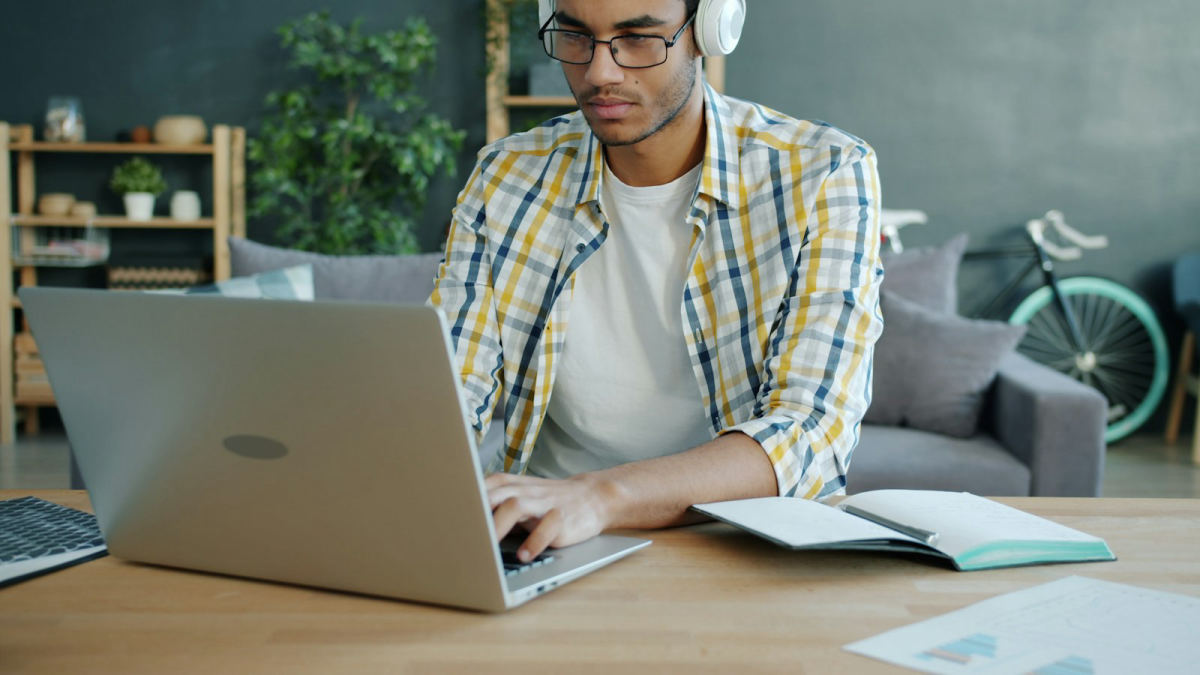 Estudiante con audífonos tomando su clase en línea desde la laptop en su casa